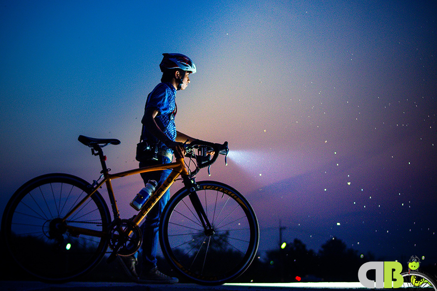 Vista de un ciclista de noche con las luces de su bicicleta encendidas.